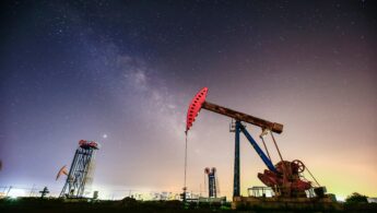 Oil plant with red pumpjack lit up against the night sky