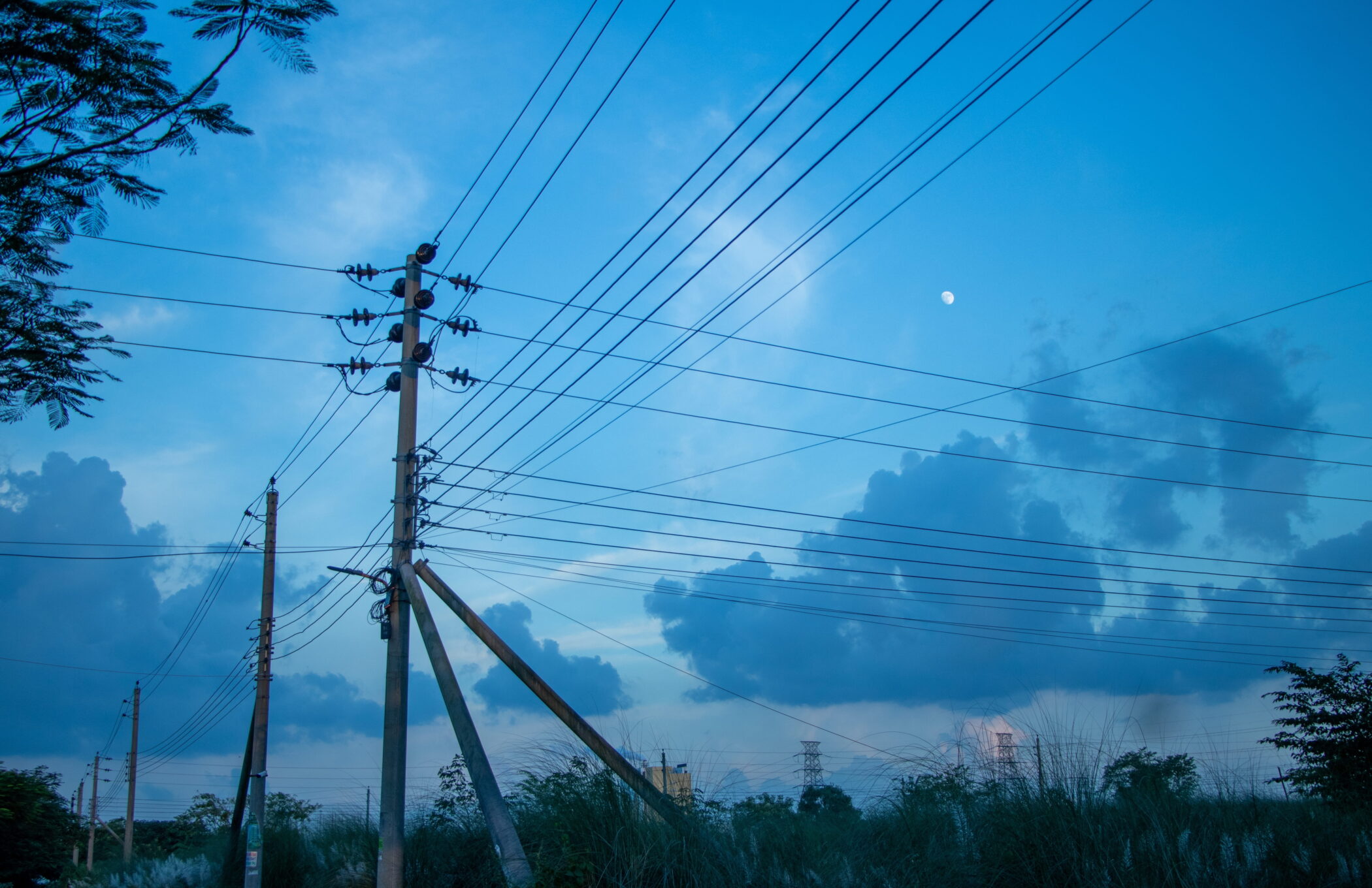 Overhead energy power lines in Bangladesh against a dark blue sky. The country is facing an energy crisis, impacting power generation, as conflict in the Middle East blocks fuel imports.